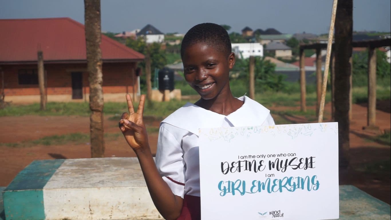 A girl holding a card that reads “I am the only one who can define myself”