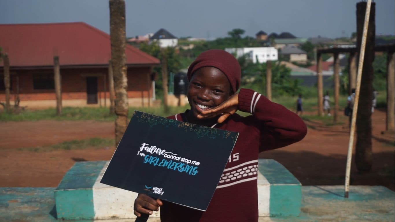 A girl holding a Girls Emerging affirmation card