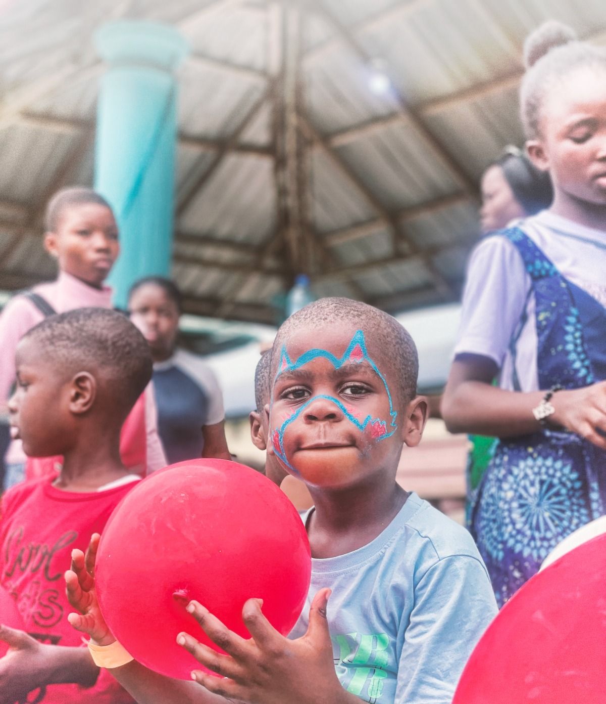 A boy with face paint holding a red balloon