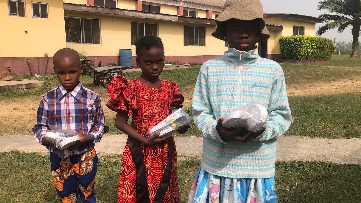 Three children holding their new pairs of shoes